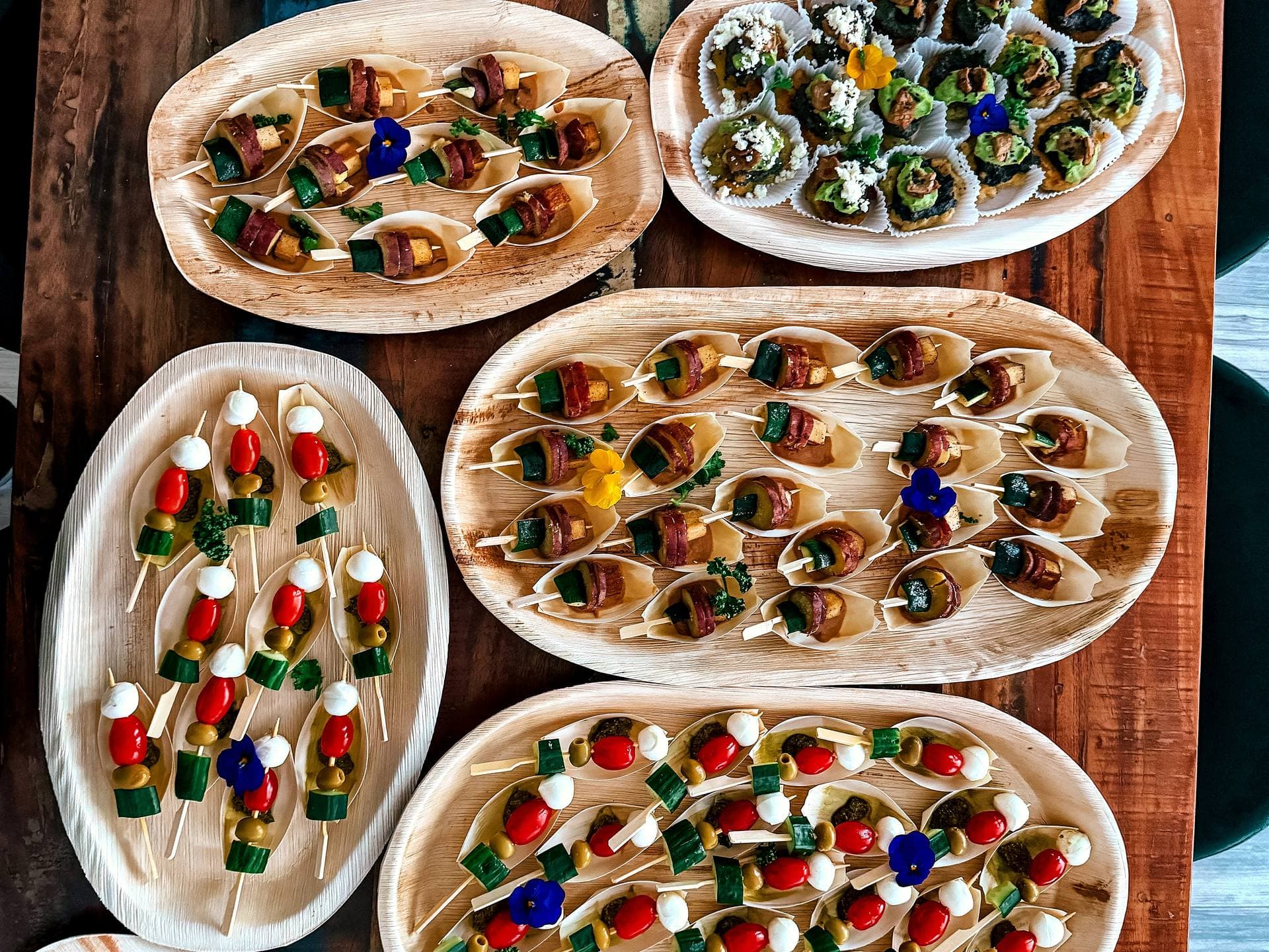 AVOCAI Fingerfood-Buffet von oben: Spieße, Süßkartoffelpuffer, Crostini und Blaubeer-Kokos-Häppchen