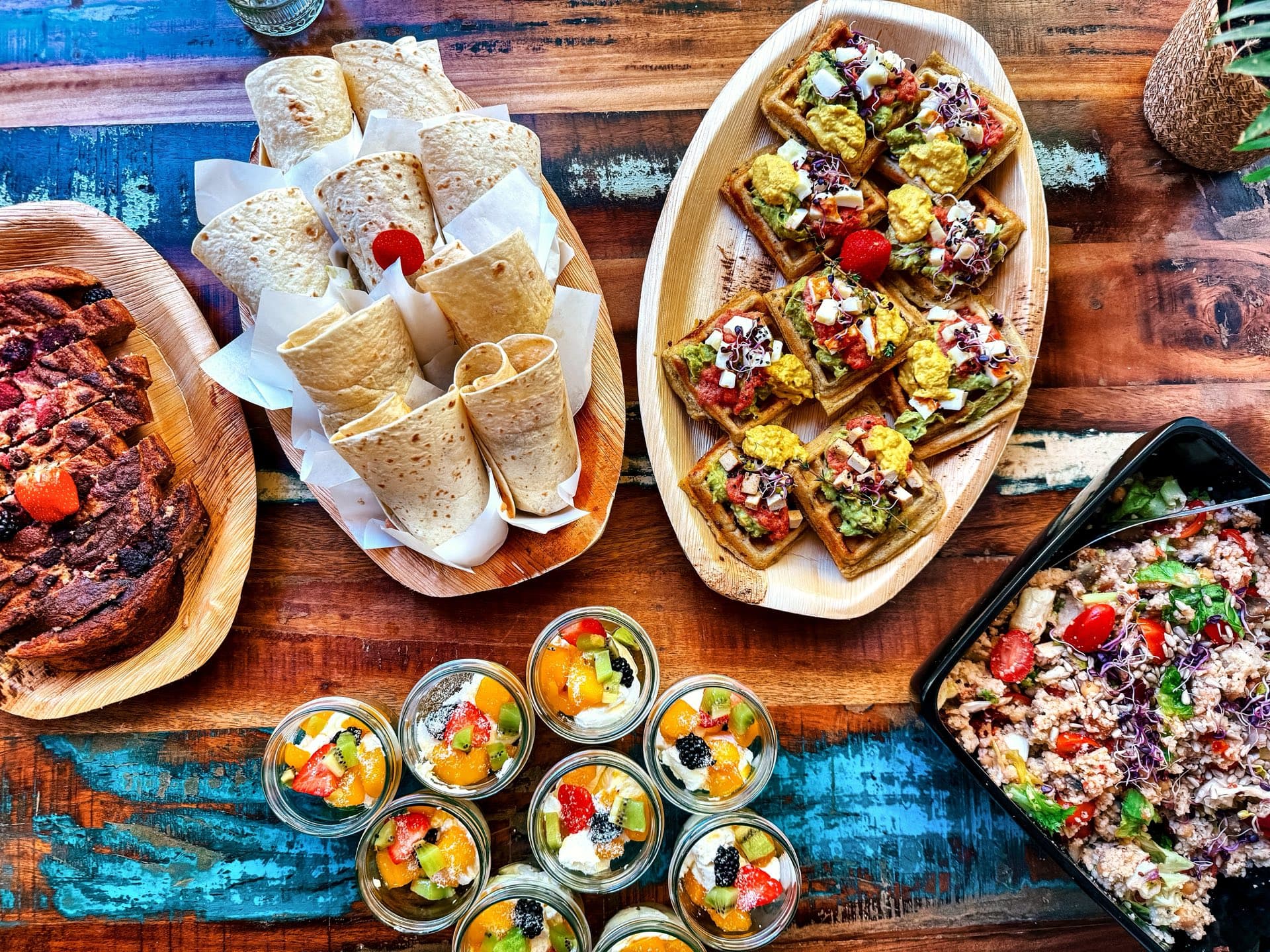 AVOCAI breakfast buffet from above: sweet potato waffles, banana bread, fruit jars and wraps